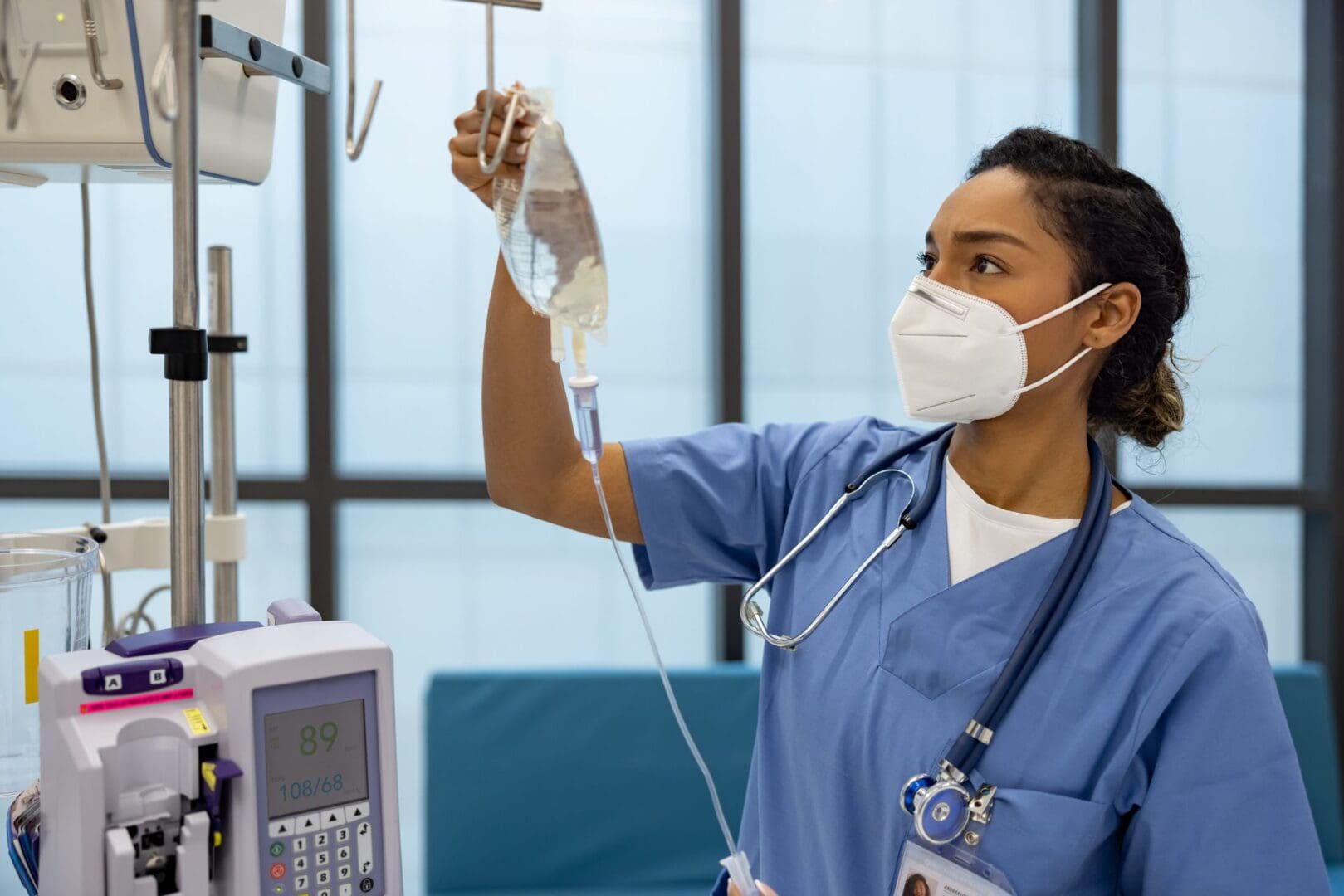 Nurse adjusting IV drip in hospital room.
